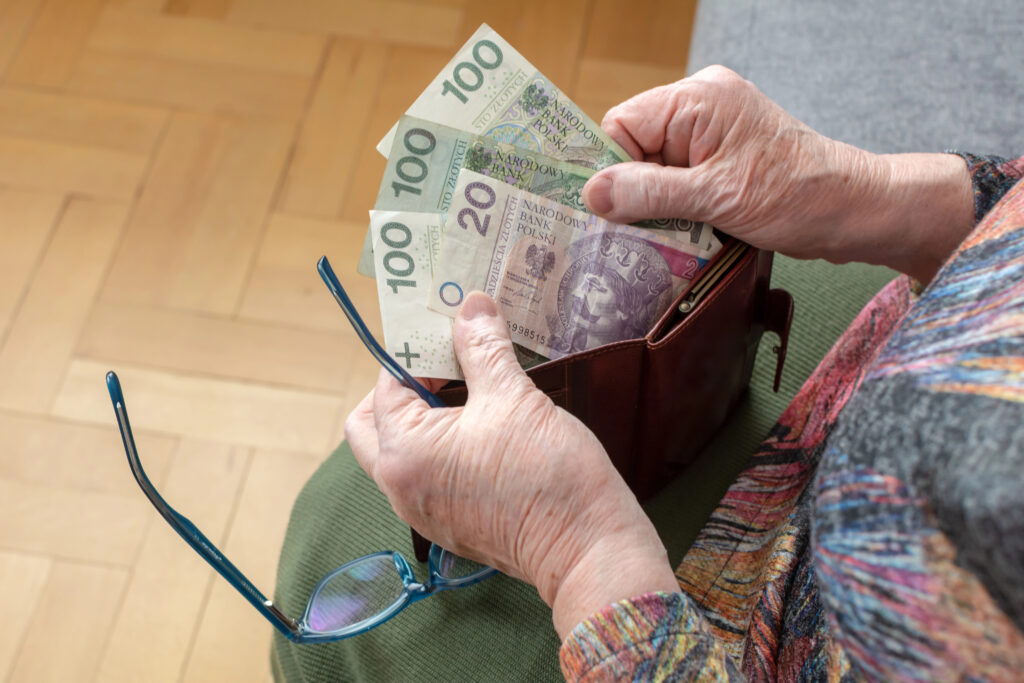 Людина рахує польські злоті біля гаманця