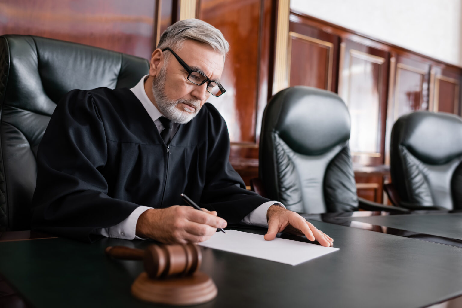 Чоловік у суддівській мантії читає документи за столом