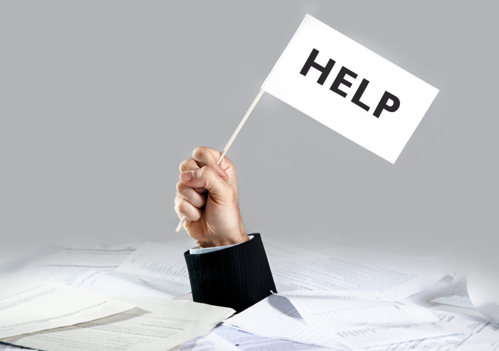Рука тримає картку з написом Help над стосом документів