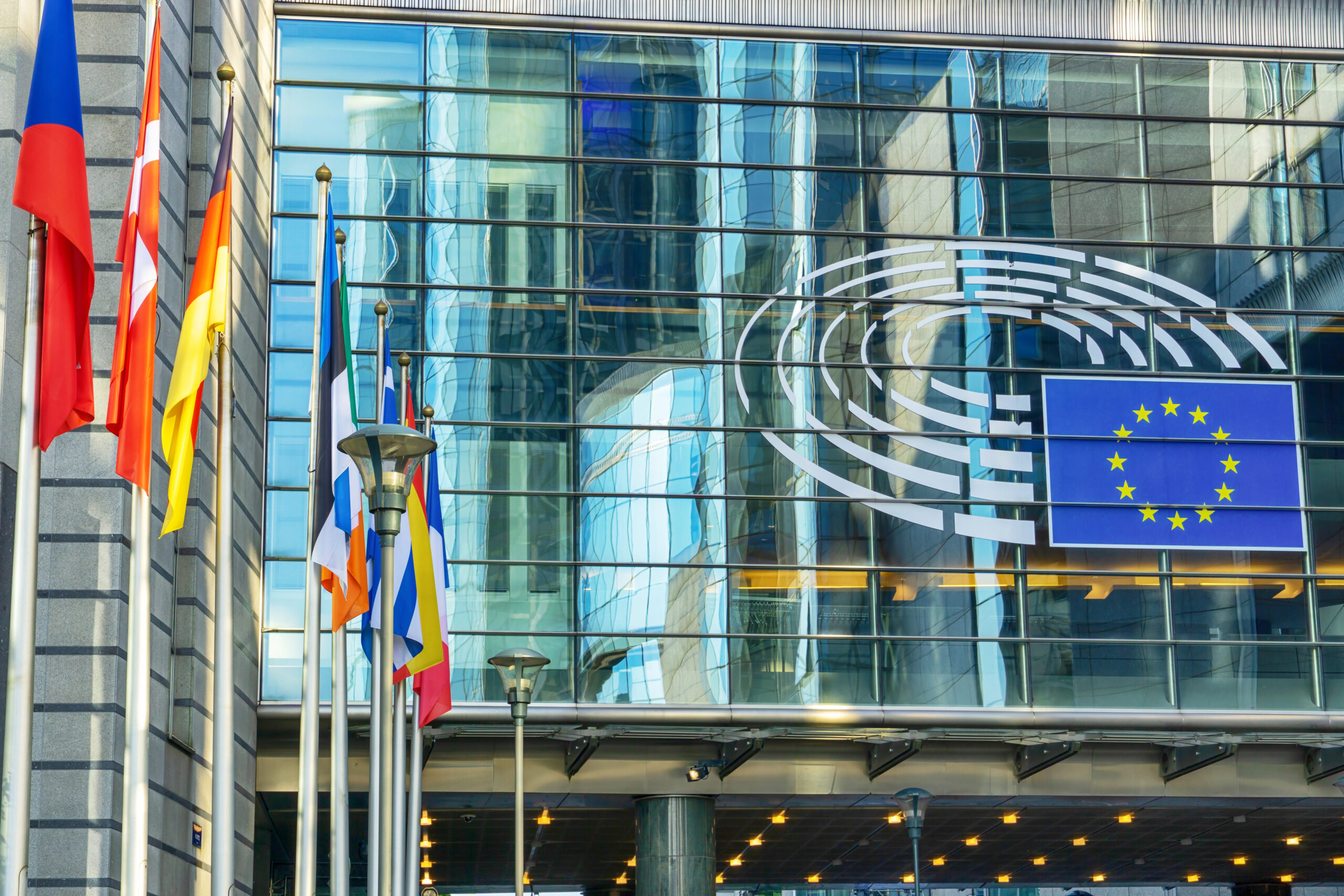 Фасад Європейського парламенту з емблемою та прапорами