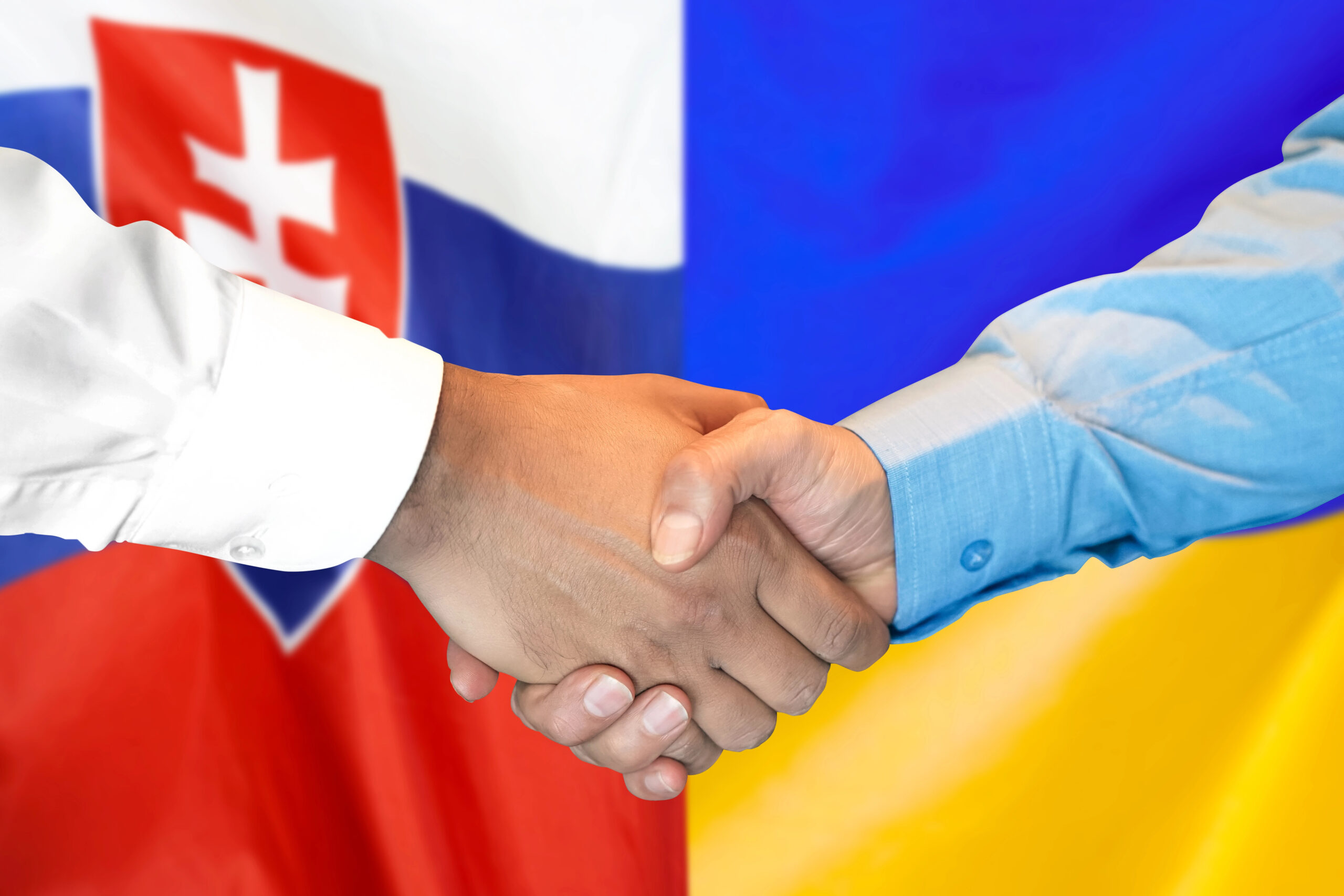Рукостискання на тлі прапорів Словаччини та України