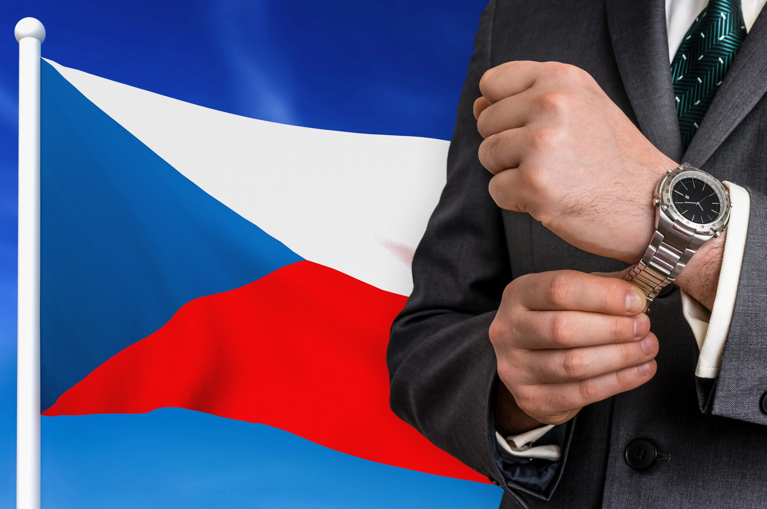 Чоловік дивиться на годинник на тлі прапора Чехії