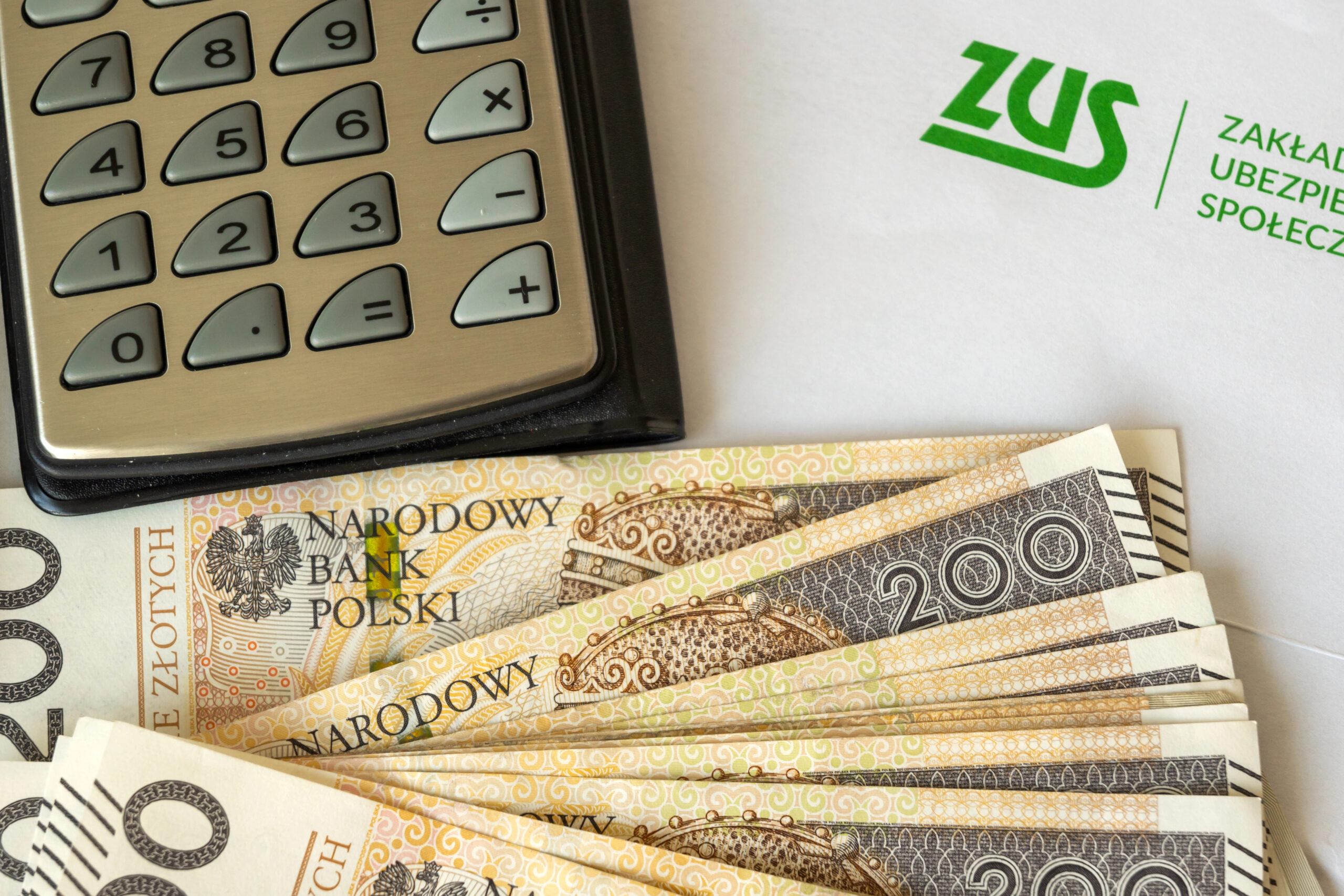 логотип ZUS, калькулятор і польські банкноти