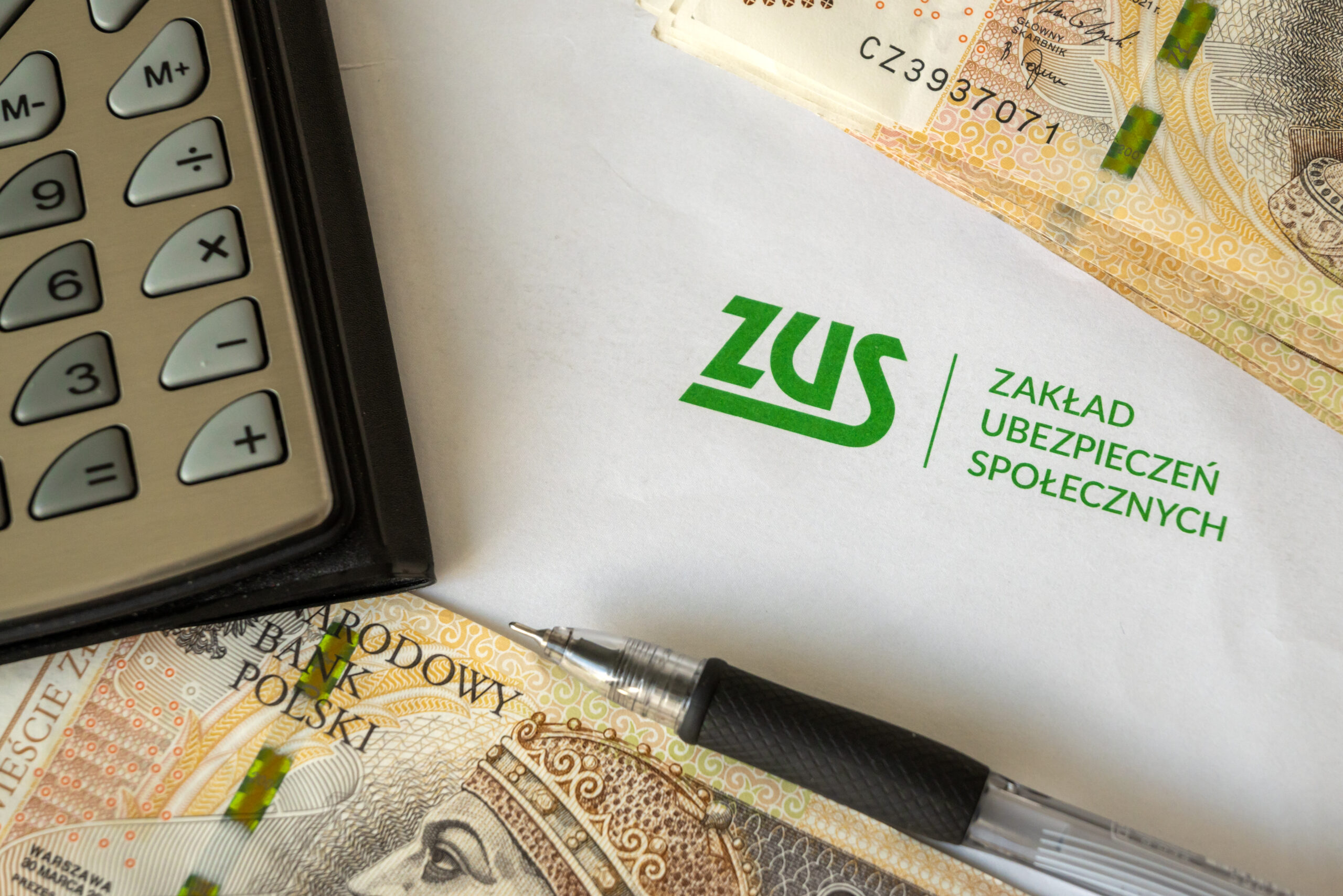 логотип ZUS, калькулятор і банкноти